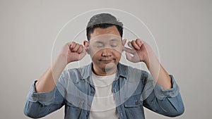 Young Asian man closing his ears dont want or avoiding to hear bad news, stress under mental pressure