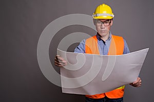 Young Asian man construction worker against gray background