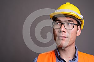 Young Asian man construction worker against gray background