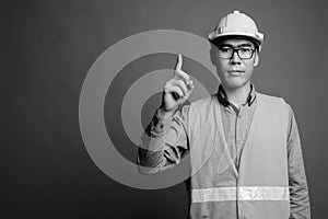 Young Asian man construction worker against gray background