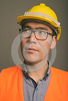 Young Asian man construction worker against gray background