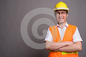 Young Asian man construction worker wearing eyeglasses against g