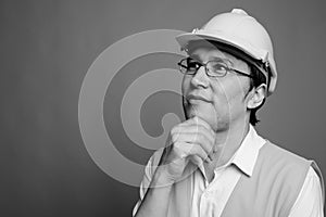 Young Asian man construction worker wearing eyeglasses against gray background