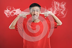 Young Asian man cover his ears with two fingers, fed up hearing hoax news
