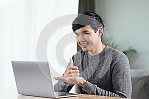 Young Asian man deaf disabled using laptop computer for online video conference call learning and communicating in sign language