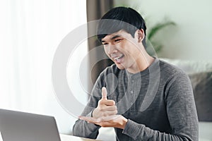 Young Asian man deaf disabled using laptop computer for online video conference call learning and communicating in sign language