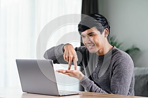 Young Asian man deaf disabled using laptop computer for online video conference call learning and communicating in sign language