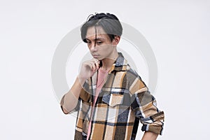 A young asian man deliberating on his next move. Strategist thinking, chin on his hand. Isolated on a white background photo