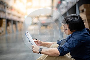 Young Asian man doing stocktaking in warehouse