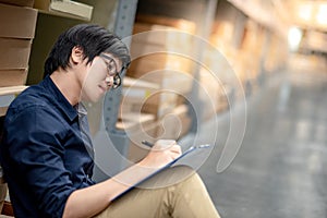 Young Asian man doing stocktaking in warehouse