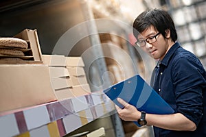 Young Asian man doing stocktaking in warehouse