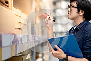 Young Asian man doing stocktaking in warehouse