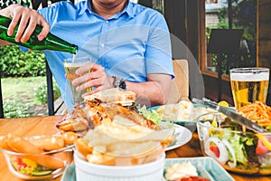 Young asian man drinking beer and eatting foods happy while enjoying home photo