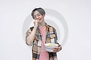 A young asian man eating popcorn in a relaxed casual way while watching a movie. Isolated on a white background