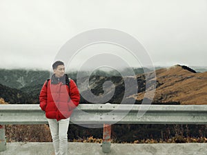 Young Asian Man Enjoying in the Wind and Mist on Mountain Top with Beautiful Landscape in Background