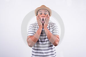 Young Asian man with hat feels shock and surprise with overly face expression.