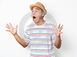 Young asian man with hat feels shock and surprise with overly face expression and looking on blank space.