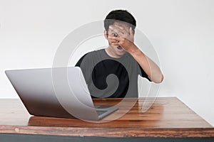 Young asian man hiding his face with hand because shocked and embarrassed by some porn videos or another forbidden thing he saw on