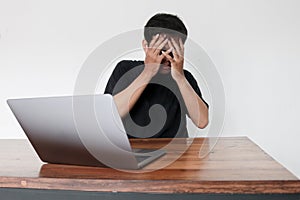 Young asian man hiding his face with hand because shocked and embarrassed by some porn videos or another forbidden thing he saw on