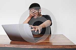 Young asian man hiding his face with hand because shocked and embarrassed by some porn videos or another forbidden thing he saw on