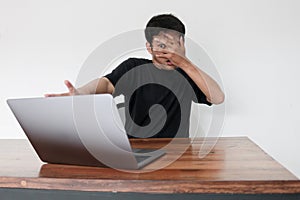 Young asian man hiding his face with hand because shocked and embarrassed by some porn videos or another forbidden thing he saw on