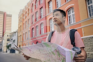 Young Asian man holding a map while exploring the city