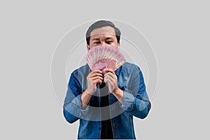 Young Asian man holding money and showing expression