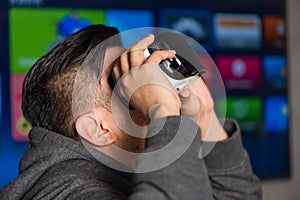 Young asian man holding virtual reality goggles on his eyes