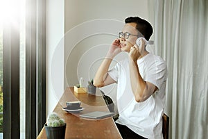 Young asian man listening music in headphones at coffee shop.