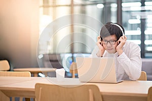 Young Asian man listening to music in workspace