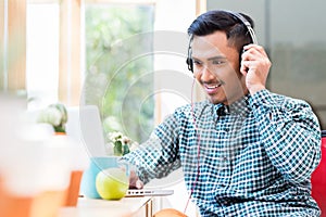 Young Asian man listening and watching an online video