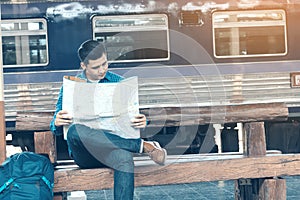 Young asian man looking map for travel at train station.