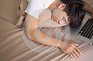 Young asian man lying in bed over his laptop