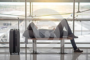 Young Asian man lying on bench in airport terminal