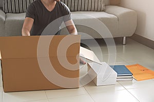 Young asian man packing and putting stuff in big cardboard box f