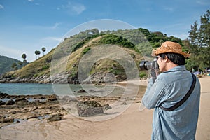 Young Asian man photographer taking photo on the beach