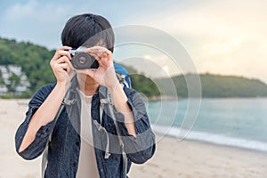 Young Asian man photographer taking photo on the beach