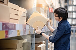 Young Asian man picking cardboard box in warehouse