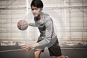 Young asian man playing basketball