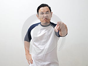 Young Asian man pointing to camera with angry cynical expression, giving warn