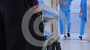 Young asian man pushing button with elevator while elderly father sitting on wheelchair at hospital.