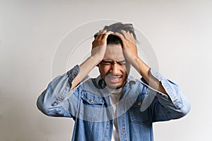 Young Asian man put hands to his head. He feeling sick and headache due to having some problems. His stress make him uncomfortable