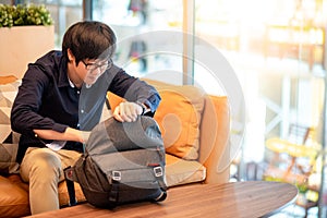 Young Asian man putting digital tablet into his bag
