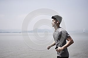 Young asian man running outdoors