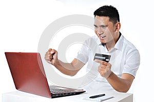 Young Asian man shopping online using debit card to pay it