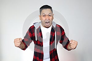 Young Asian man shouting loud because of anger. Concept of rage aggression mad frustration