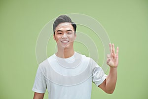 Young asian man showing ok hand sign and smiling