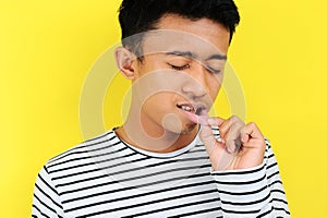 Young Asian man showing ulcer or blister in his mouth at camera, isolated on yellow