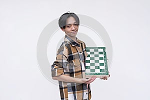 A young asian man with side-parted hair holding a chess board. Isolated on a white background