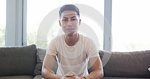 Young Asian man sits comfortably at home on video call